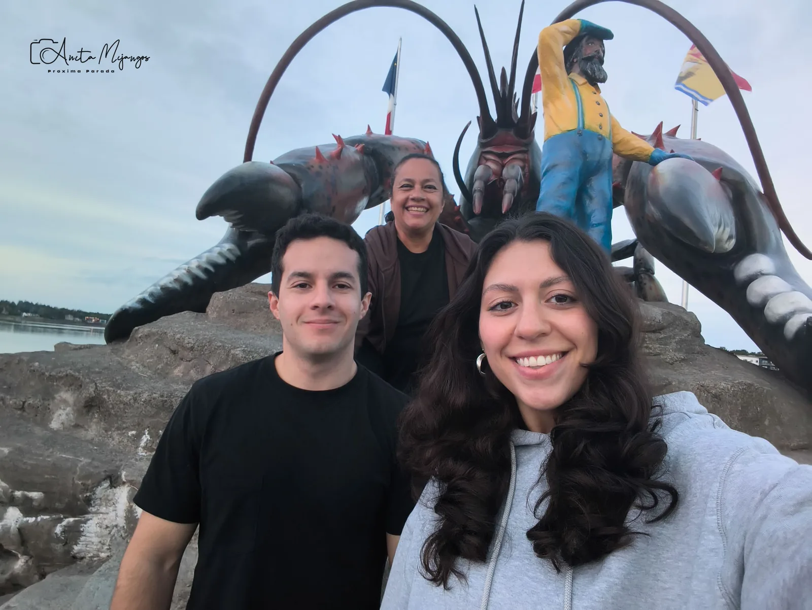 Tres personas frente a la escultura de langosta de Shediac