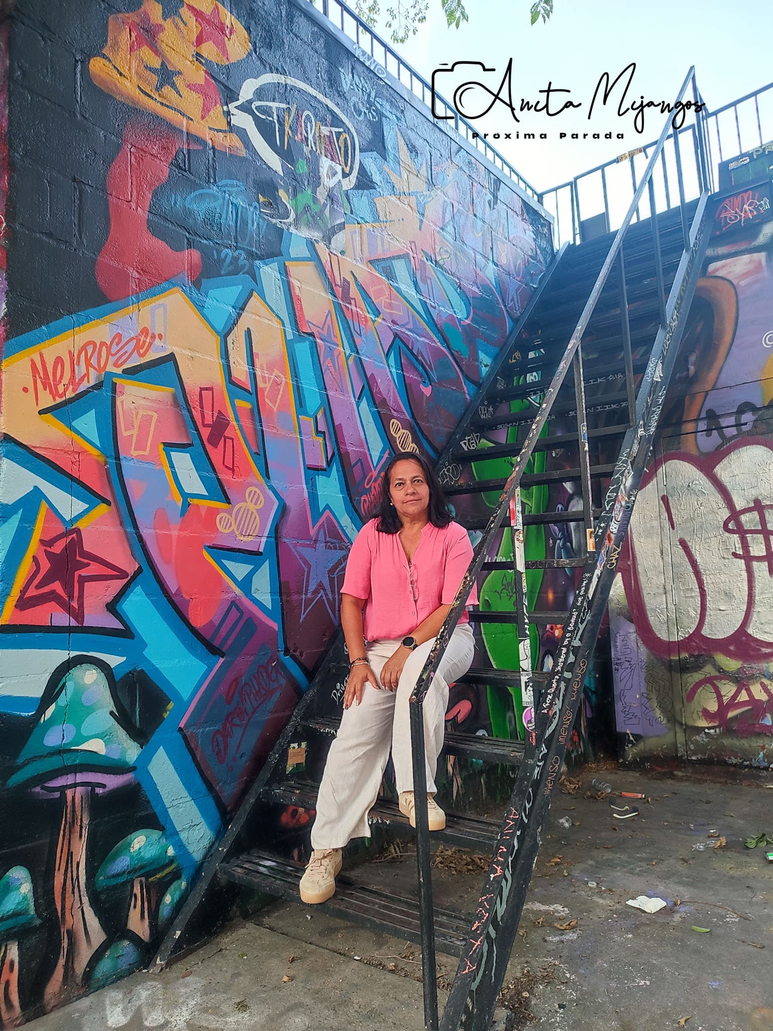 Anita Mijangos en Toronto, sentada frente a un mural colorido